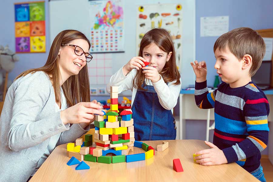 woman and two children playing with blocks