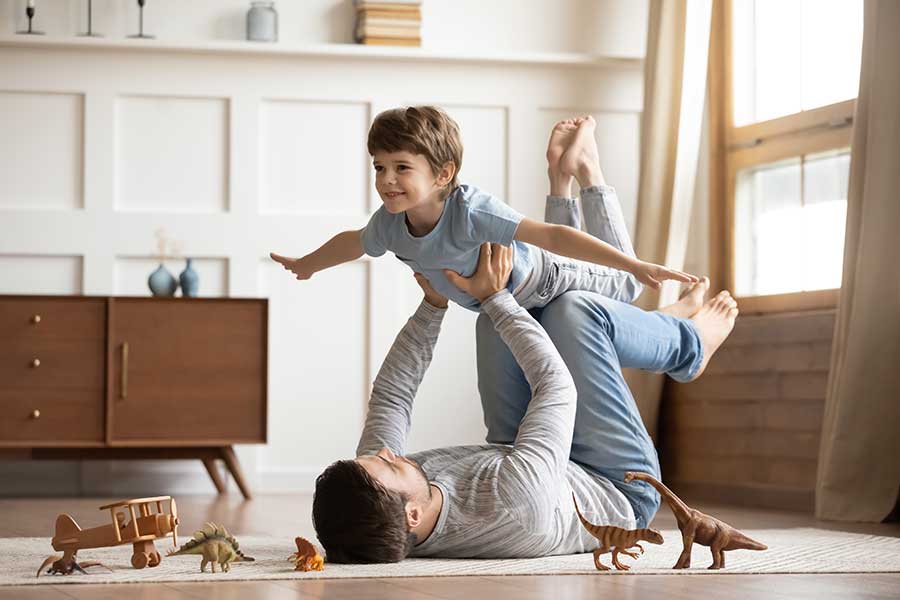 man lifting young child off the floor and playing
