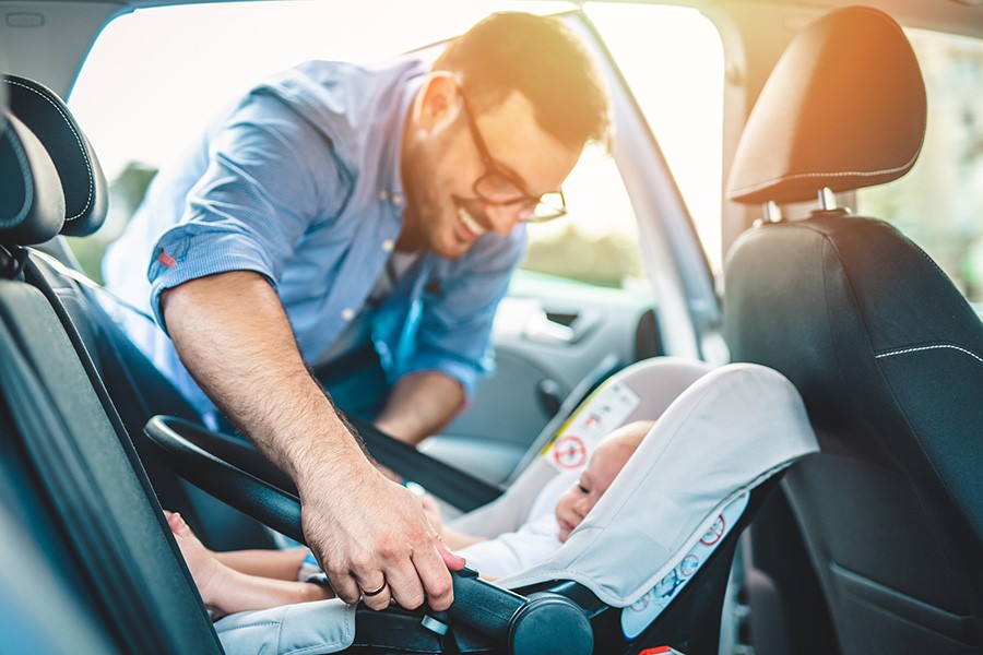 dad putting baby in car seat