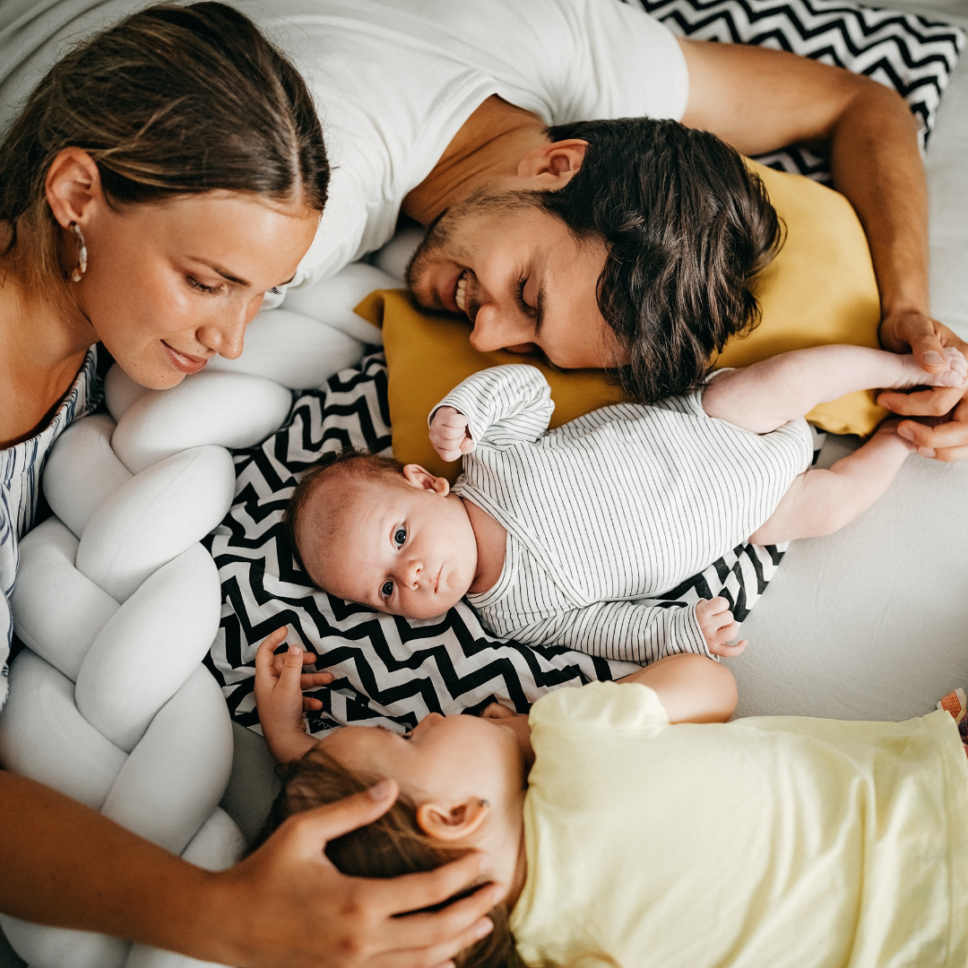 Parents cuddling with newborn and toddler